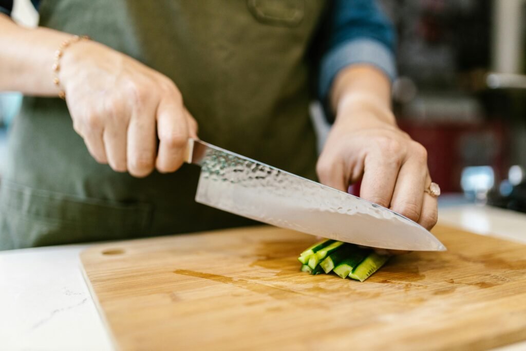 Hands slicing cucumber on cutting board, highlighting freshness in food preparation.